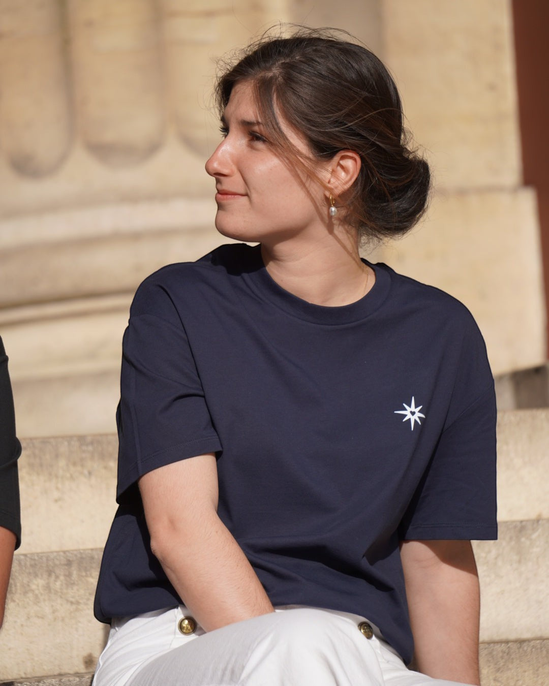 Woman wearing a navy Fidem crewneck t-shirt with a small white star and heart logo on the chest